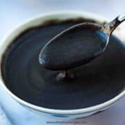 Chinese black sesame soup dessert on a spoon dripping into the bowl horizontal