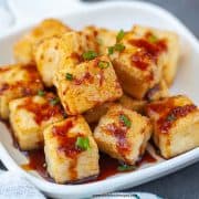 crispy tofu on a white plate with teriyaki sauce