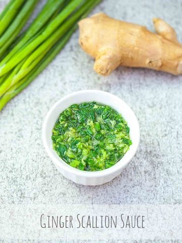 ginger scallion sauce in a white container with green onion and ginger background