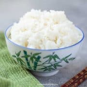 a bowl of cooked jasmine rice with a pair of chopstick