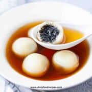 tang yuan with black sesame seeds filling cut open on the spoon