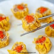 cooked shumai or siu mai on silver chopsticks horizontal