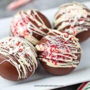 four decorated hot chocolate bombs or balls on the white plate