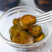 Chinese pickled cucumbers in the glass container and on a fork close up