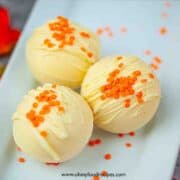 three pumpkin spice white chocolate bombs on the white plate