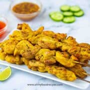 grilled or cooked Thai chicken satay on the plate with sauces on the sides