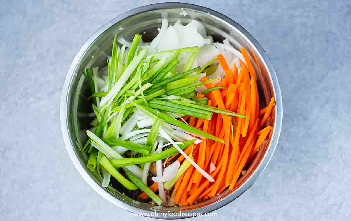 cut green onion, onion and carrot in the bowl with beef top view